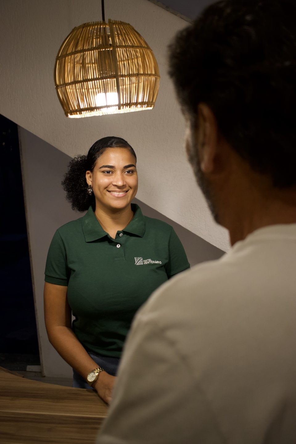 Recepcionista do hotel atendendo um hóspede no balcão da recepção