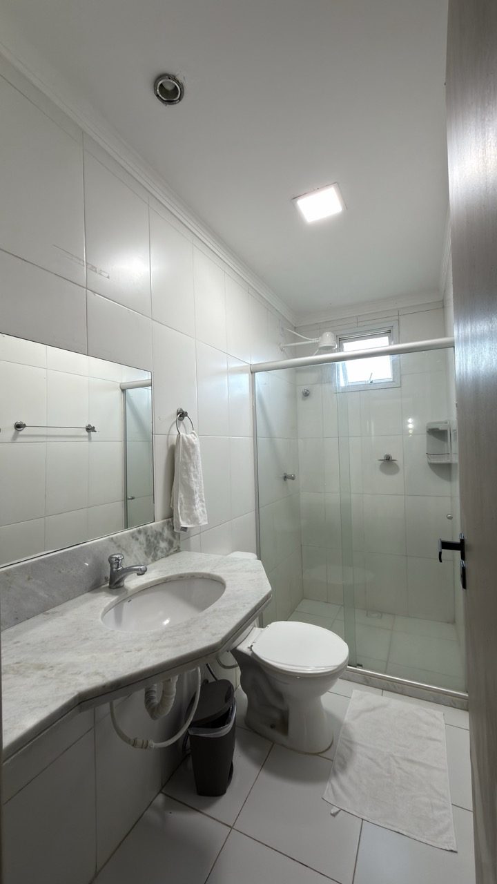 Banheiro do quarto com box de vidro, bancada de pedra e espelho