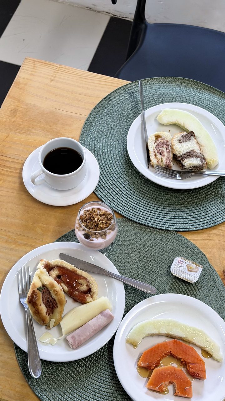 Mesa posta com café, bolo de rolo, presunto, queijo, mamão e vitamina