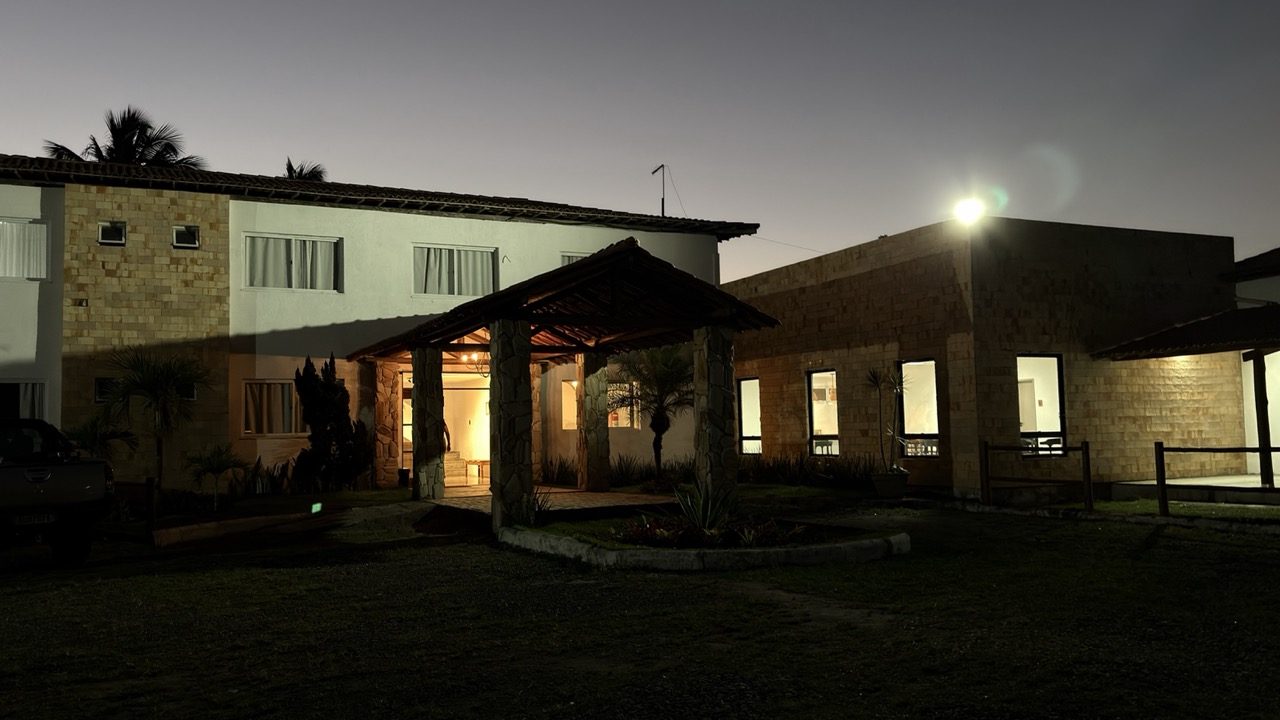 Fachada do Hotel Centenário ao anoitecer, com o pórtico de madeira iluminado