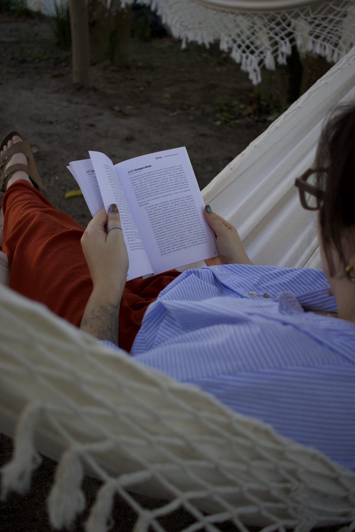 Hóspede deitada na rede do quintal lendo um livro no fim da tarde